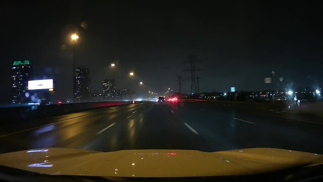 Point of view of car driving view through city highway. Fast driving plate on Gardiner Expressway, Toronto, Ontario, Canada. Travelling dash cam car camera view moving forward, wipers on rainy night.