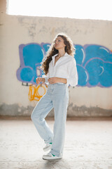 A stylish modern girl poses on the street against the background of graffiti.