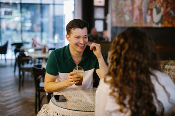 Happy young couple talking over a cup of coffee in a cafe, man and woman in a coffee shop on a date.