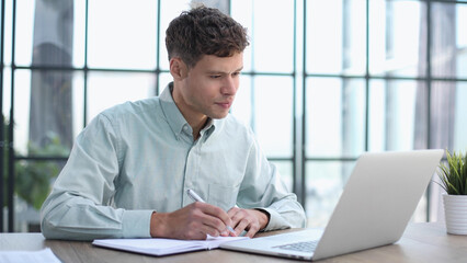 Shot of a young businessman using a laptop in a modern office