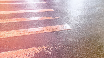 Pedestrian presinct on rainy day. Wet asphalt road with white stripes. Shiny street. Urban night...