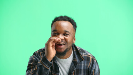 A man, close-up, on a green background, tells a secret