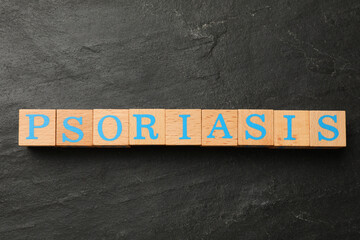 Word Psoriasis made of wooden cubes with letters on dark gray textured table, top view