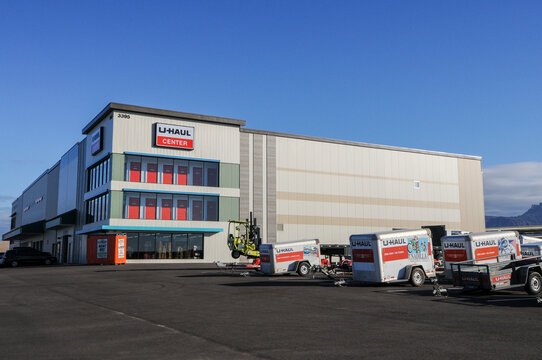An exterior front view of a large U-Haul Center in Apache Junction, Arizona, with rental cargo trailers parked outside the facility