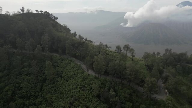 Aerial tracks motos on twisty mtn road near Mt Bromo volcano on Java
