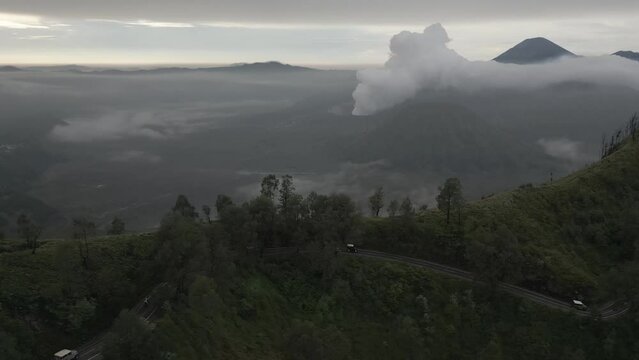 Convoy of tourism trucks on twisted mtn road near Mt Bromo on Java