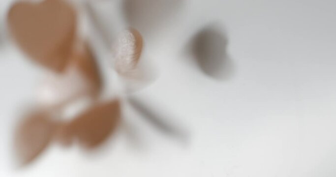 Heart pink decorative elements falling close up, studio vertical 4K