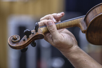 man playing violin, view of hand holding violin, violinist playing at concert
