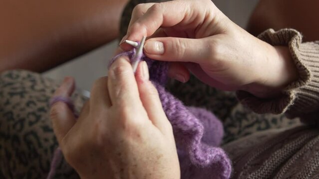 Close up of hands knitting a purple piece