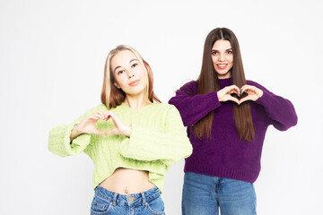 Studio shot of two young women friends wearing sweaters isolated over white background