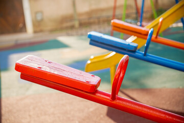 perspective of a pair of colorful seesaws on a children's playground