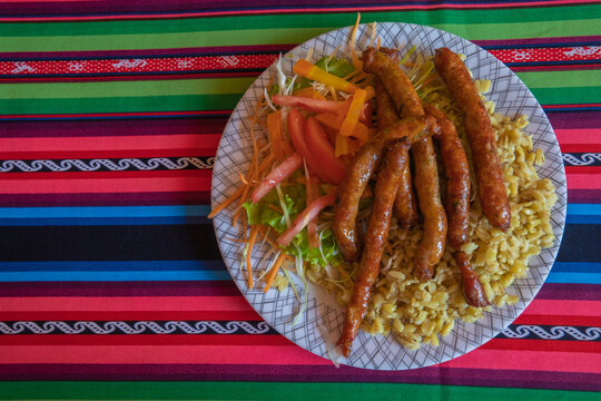traditional Bolivian food, "chorizos de Tarata", plate with wheat and vegetable salad, on a "aguayo" tablecloth