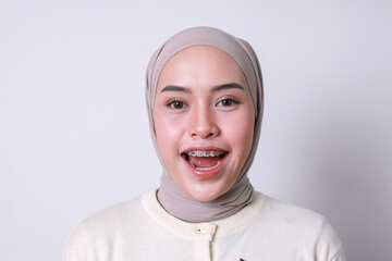 Closeup view of beautiful young muslim girl with dental braces and hijab looking at camera with...