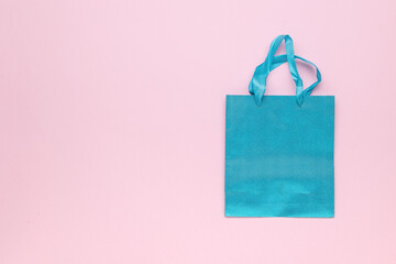 Top view of a blue gift bag on a pink background.