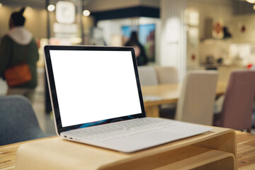 The blank screen of the laptop on the wooden table, the background of the shopping mall, the...