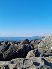 Fototapeta na wymiar Jeju Island's sea with black basalt rocks.