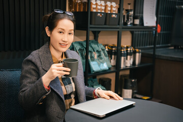 A portrait of a professional investment adviser Asian woman was sitting in front of the desk in front of the laptop, watching the camera and smiling.