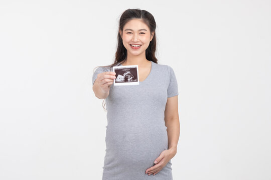 Happy Pregnant Woman standing smile holding ultrasound image stroking big belly with love isolated on white background,Pregnancy of young woman enjoy with future life,Motherhood and Pregnant Concept