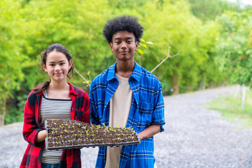 Portrait of Happy teenage boy and girl growing organic vegetable on agriculture farm field in the garden. School student learning and working nature and gardening healthy food for sustainable living.