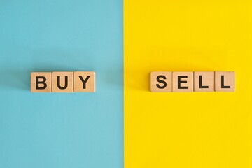 Buy versus sell in business and investing concept. Wooden blocks typography in bright blue and...