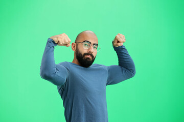 A man, on a green background, close-up, shows strength