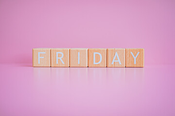 Wooden blocks form the text "FRIDAY" against a pink background.