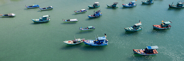 Fototapeta na wymiar Aerial view of multiple colorful fishing boats scattered on calm sea water