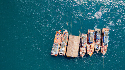 Aerial view of a cluster of traditional fishing boats on a sparkling blue ocean