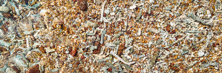 Clear water ripples over a colorful pebble-covered riverbed, abstract nature background