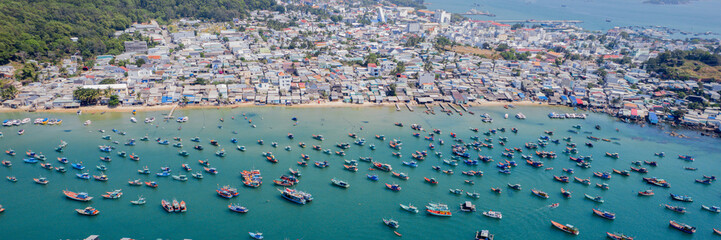 Aerial view of a bustling coastal town with numerous boats anchored in a calm bay
