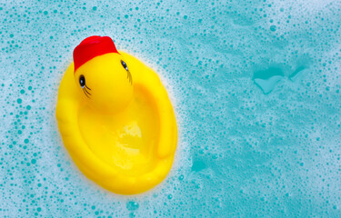 Yellow duck rubber toy with foam bubbles in blue basin