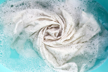 Woman's lace dress soaked in water dissolved detergent with white foam bubble. Laundry concept