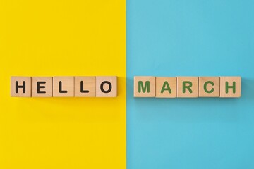 Hello month of March concept. Wooden blocks typography in bright blue and yellow background.