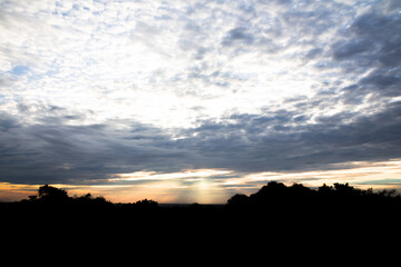 Obraz premium Panoramic cloudscape with the sun rays radiating from behind the cloud.Phnom Bakheng sunset view Angkor Wat, Siem Reap, Cambodia