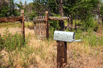 Abandoned home fence, gate and mailbox with bullet holes in Wyoming, USA
