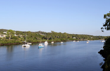Fototapeta na wymiar Serene view of the Boyne River with boats and trees in Boyne Island/Tannum Sands in Queensland, Australia