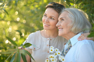 Beautiful elderly woman with her daughter walking in park