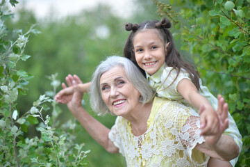 Portrait of happy grandmother and granddaughter in park
