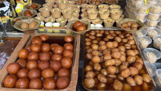 Closeup shot of Gulab Jamuns and Rasgullas kept on a plates made up of leaf in a sweet shop in Kolkata, India.