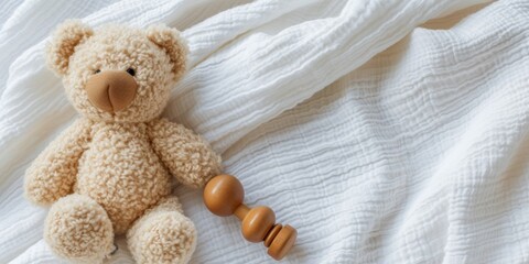 Teddy bear and natural wooden rattle toy on white blanket throw background. Top view, copyspace - obrazy, fototapety, plakaty