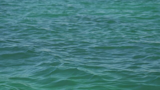 Aqua blue water texture ripples during sunny day ocean background slomo