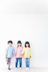 壁に並ぶ3人の幼稚園児