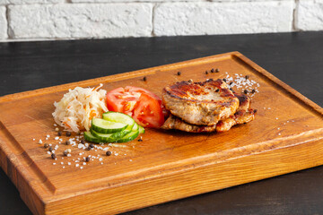 Pork steak with fresh vegetables on a wooden board