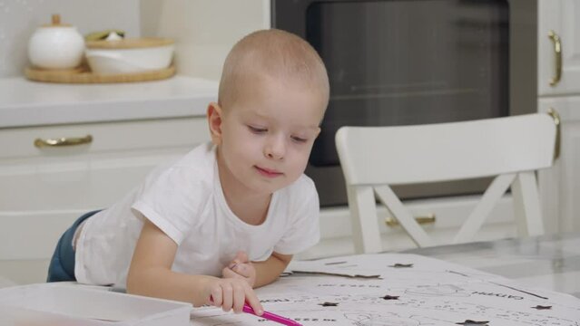 3-year-old child drawing with felt tip pens on large sheet of cardboard. Cute little boy drawing at home.