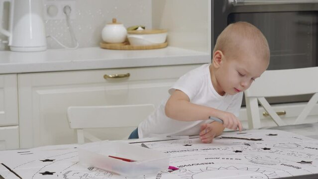 3-year-old child drawing with felt tip pens on large sheet of cardboard. Cute little boy drawing at home.
