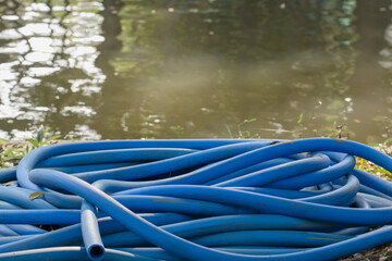 Close up shot of blue hose roll along riverbank.