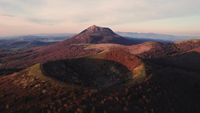 drone shot flying over puy pariou and revealing the Puy de Dome in the background at sunrise, Clermont Ferrand, Auvergne, France