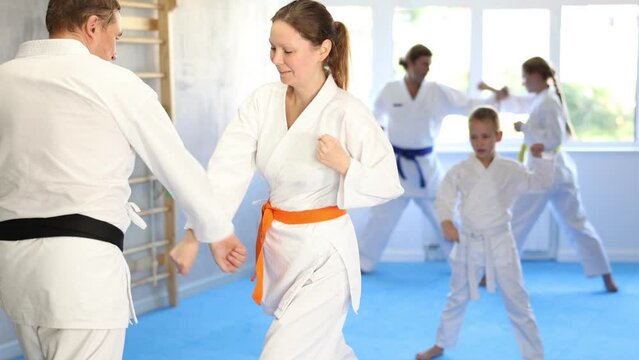 Woman is paired with man teacher to learn how to strike and rehearses blocking opponent, using karate technique
