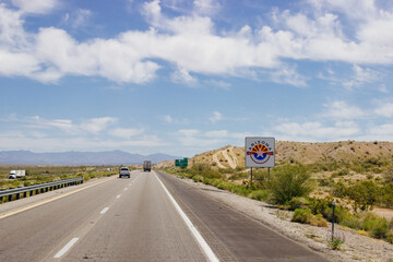 Beautiful blue sky with fluffy clouds over the highway on a spring day. Arizona sign. Scenic road in Arizona, USA on a sunny summer day. Arizona, USA - 17 April 2020