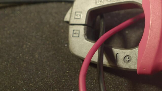 Close up: Clamp multimeter tool measures current in red, black wires